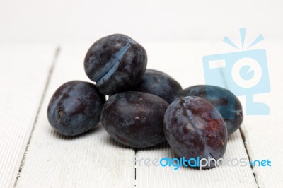 Tasty Purple Plums Isolated On A White Wooden Background Stock Photo