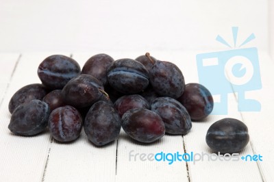 Tasty Purple Plums Isolated On A White Wooden Background Stock Photo