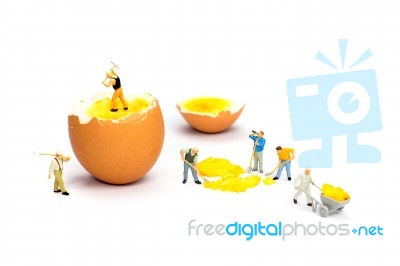 Team Of Miniature Human Figurines Transporting Chicken Egg Yolk Stock Photo