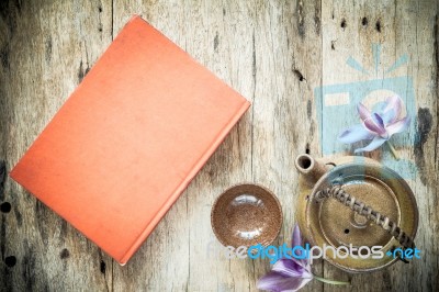 Teapot And Red Book On Old Wooden Background Stock Photo