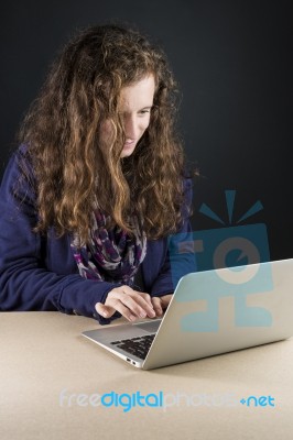 Teen Sitting At Table With A Laptop Stock Photo