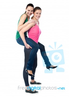 Teenage Girl Piggybacks Her Friend Stock Photo