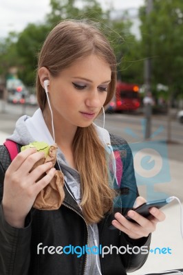 Teenager Eating Cake Looking In Phone Stock Photo