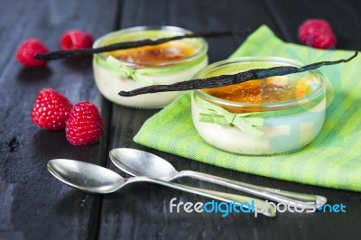 The Creme Brulee In Glass Dish With Vanilla Pods And Raspberries… Stock Photo