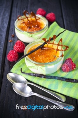 The Creme Brulee In Glass Dish With Vanilla Pods And Raspberries… Stock Photo