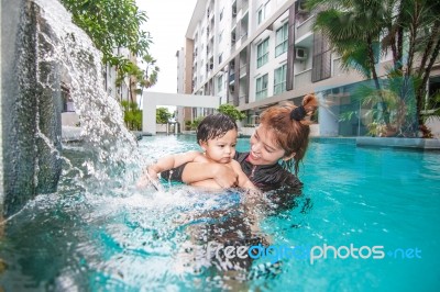 The Kid And Mom Play Together In The Pool Stock Photo