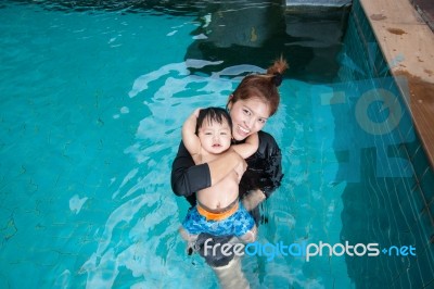 The Kid And Mom Play Together In The Pool Stock Photo