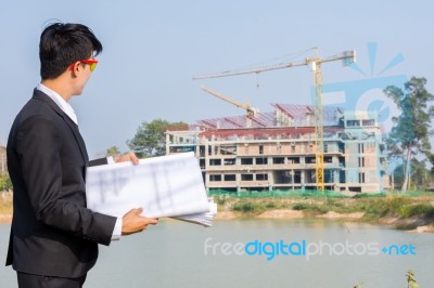 The Young Businessman Holds A Blueprint And Looks At The Structu… Stock Photo