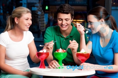 Three Friends Enjoying Tempting Dessert Stock Photo