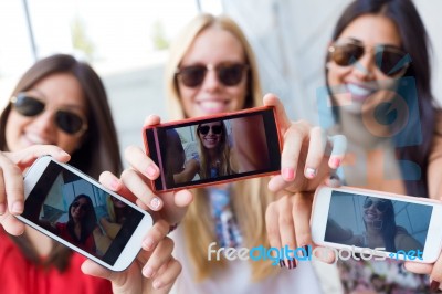 Three Friends Taking Photos With A Smartphone Stock Photo