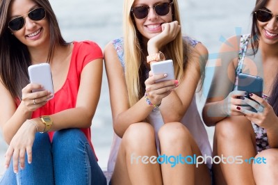 Three Girls Chatting With Their Smartphones At The Campus Stock Photo