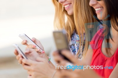 Three Girls Chatting With Their Smartphones At The Campus Stock Photo