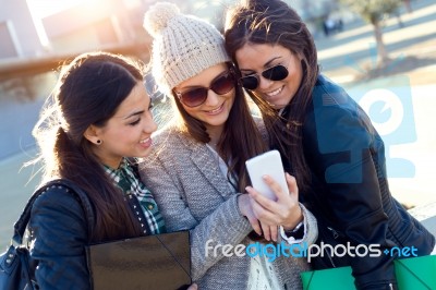 Three Students Girls Using Mobile Phone In The Campus Stock Photo