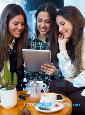 Three Young Woman Using Digital Tablet At Cafe Shop Stock Photo