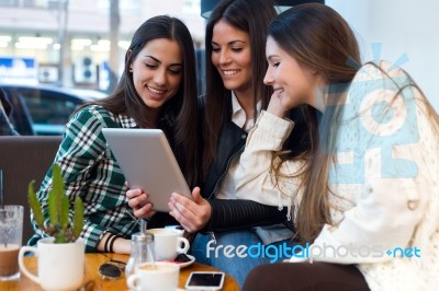 Three Young Woman Using Digital Tablet At Cafe Shop Stock Photo