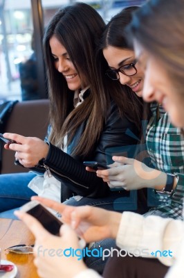 Three Young Woman Using Mobile Phone At Cafe Shop Stock Photo