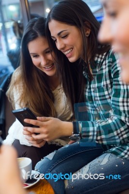 Three Young Woman Using Mobile Phone At Cafe Shop Stock Photo