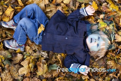 Toddler Blond Boy With Blue Eyes Lays On Bed Of Autumn Fallen Le… Stock Photo