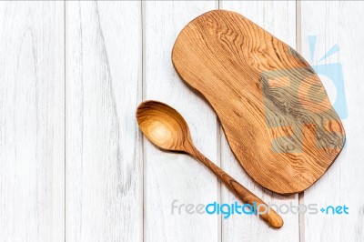 Top View Of Wooden Cutting Board With Spoon On White Wooden Table Stock Photo