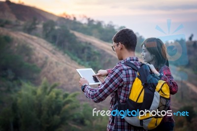 Tourists Look At A Map On The Tablet On Mountain Stock Photo