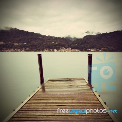 Tranquil Scene Of Old Wooden Pier And Misty Italian Alps Mountai… Stock Photo