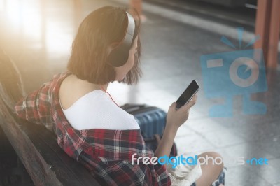 Traveler Girl Using Tablet And Headset With A Luggage Sitting An… Stock Photo