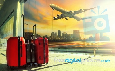 Traveling Luggage In Airport Terminal Building And Jet Plane Flying Over Urban Scene Stock Photo