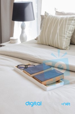 Tray Of Books And Glass On Bed Stock Photo