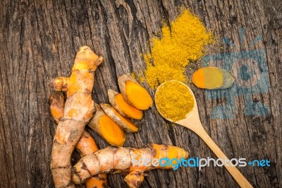 Turmeric Powder In Spoon And Roots On Wooden Plate Stock Photo