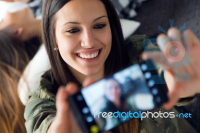 Two Beautiful Young Woman Using Mobile Phone At Home Stock Photo