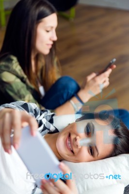 Two Beautiful Young Woman Using Mobile Phone At Home Stock Photo