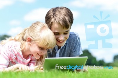 Two Children Lying Down And Using Tablet Pc Stock Photo