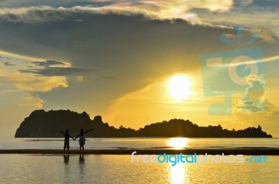 Two Children Standing On The Beach Watching The Sunrise Stock Photo