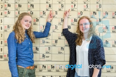 Two Female Students Pointing At Periodic Table In Chemistry Less… Stock Photo