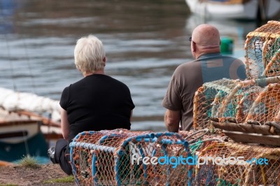 Two People Sitting On The Quayside At Dunbar Stock Photo