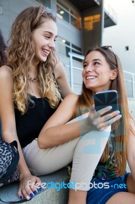 Two Students Having Fun With Smartphones After Class Stock Photo