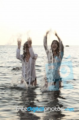 Two Women In The Water Splashing And Having Fun Stock Photo