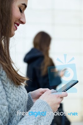 Two Young Businesswoman Using Mobile Phone In The Street Stock Photo