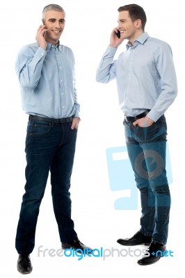 Two Young Men Talking Through Mobile Phone Stock Photo