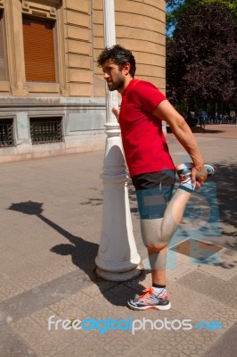 Urban Athlete Doing Stretching Next To A Lamppost Stock Photo