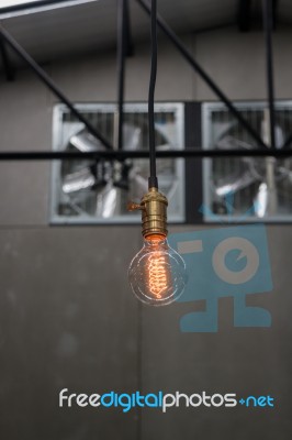 Vintage Hanging Light Bulb Over Gray Room Stock Photo