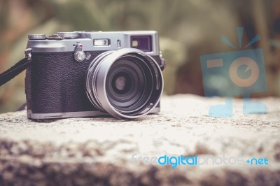 Vintage-style Digital Camera On Boulder Over Blurred Nature Backgrouna Stock Photo