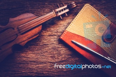 Violin And Notebook With Pen On Grunge Dark Wood Background Stock Photo