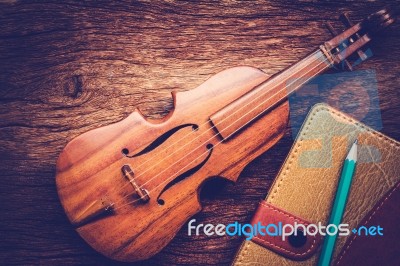 Violin And Notebook With Pencil On Grunge Dark Wood Background Stock Photo