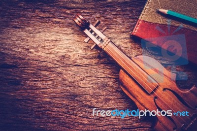 Violin And Notebook With Pencil On Grunge Dark Wood Background Stock Photo