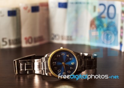 Watch Against The Background Of Banknotes Stock Photo