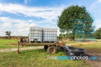 Water Containers On Cart For Cattle In Meadow Stock Photo