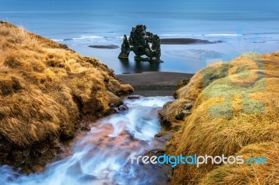 Waterfall And Hvitserkur Is Spectacular Rock In The Sea On The Northern Coast Of Iceland Stock Photo