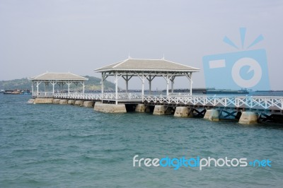 White Long Wooden Bridge Pavilion Into The Sea, Cargo Ships In The Sea Stock Photo