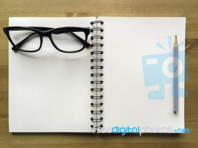 White Paper Note Book With Grey Pencil And Black Glasses On Wood… Stock Photo